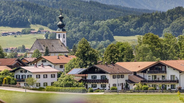 A village with traditional houses, a church with a bell tower, and mountains in the background. - Appartement 4 "rauschberg" für 2 Personen, 32 m² (Inzell)