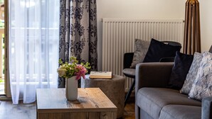 A living room with a sofa, a coffee table, a lamp, and a window with curtains.