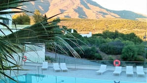 Une piscine dotée de chaises longues et d’une bouée de sauvetage, offrant une vue sur un paysage montagneux.