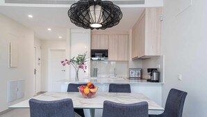 Une cuisine moderne dotée d’un îlot central, d’une table à manger avec des chaises et d’un luminaire décoratif suspendu.