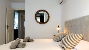 Une chambre à coucher avec un lit, deux oreillers, une lampe de chevet, un miroir et une porte.