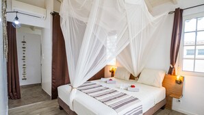 A bedroom with a bed, a bedside table, a nightstand, a window, and a door. - Villa Familiale Avec Piscine Privée à 5 Minutes de la Plage! (Sainte-Rose)