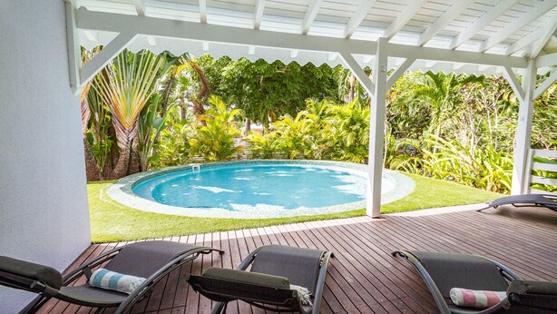 A covered outdoor area with a pool, lounge chairs, and lush greenery. - Villa Familiale Avec Piscine Privée à 5 Minutes de la Plage! (Sainte-Rose)