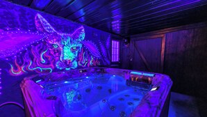 A hot tub with a colorful mural of a wolf on the wall.