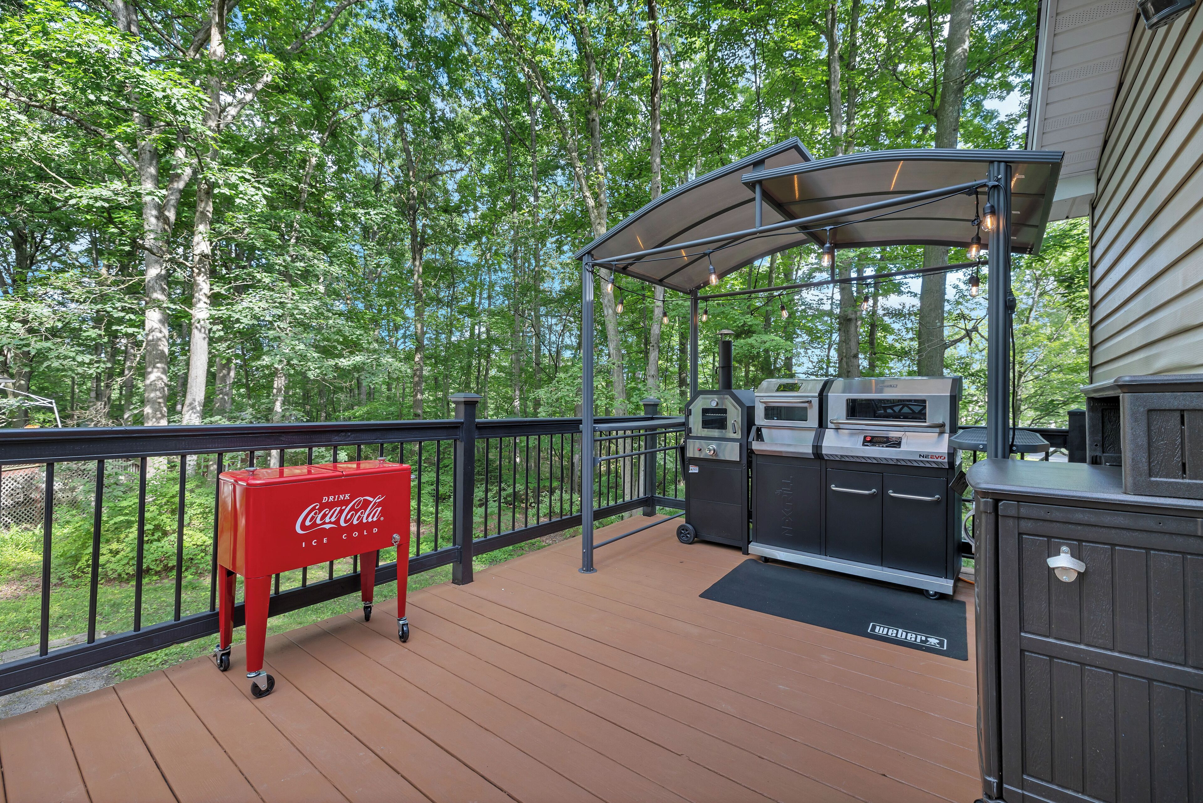 Una terrazza esterna con un barbecue, un refrigeratore Coca-Cola e un'area salotto coperta.