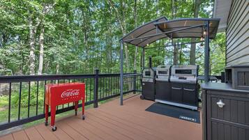 Una terrazza esterna con un barbecue, un refrigeratore Coca-Cola e un'area salotto coperta.