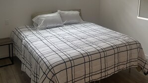 A bedroom with a bed, a window, and a small table.