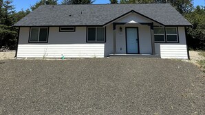 A single-story house with a grey roof and white siding, number 358, with a small porch and a door.