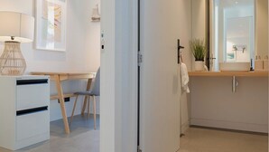 A modern, well-lit room with a desk, chair, and a large mirror reflecting a bathroom vanity. - 3 min to The Remarkables / Lakefront Spa Luxury (Kawarau Falls)