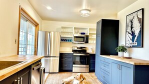 A modern kitchen with stainless steel appliances, wooden countertops, and a dog lying on the floor.