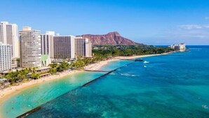 Ein Küstenhotel mit mehreren Hochhäusern, einem Strand und einem Berg im Hintergrund.