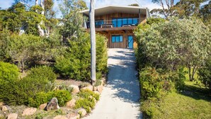 Une maison moderne à deux étages, dotée d’un porche abrité et d’un chemin menant à l’entrée.