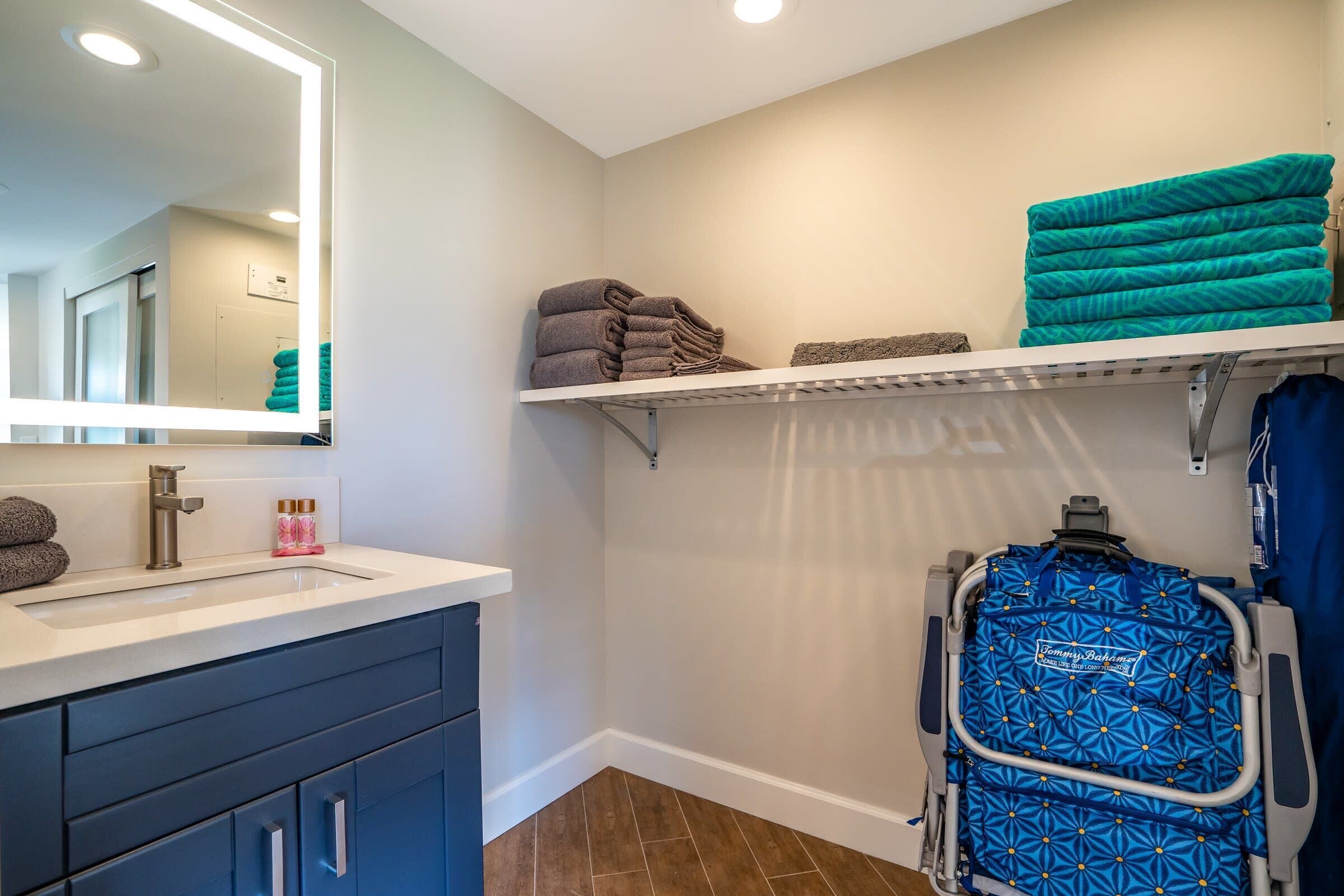 A bathroom with a sink, mirror, towel racks, and a wheelchair.