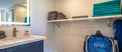 A bathroom with a sink, mirror, towel racks, and a wheelchair.