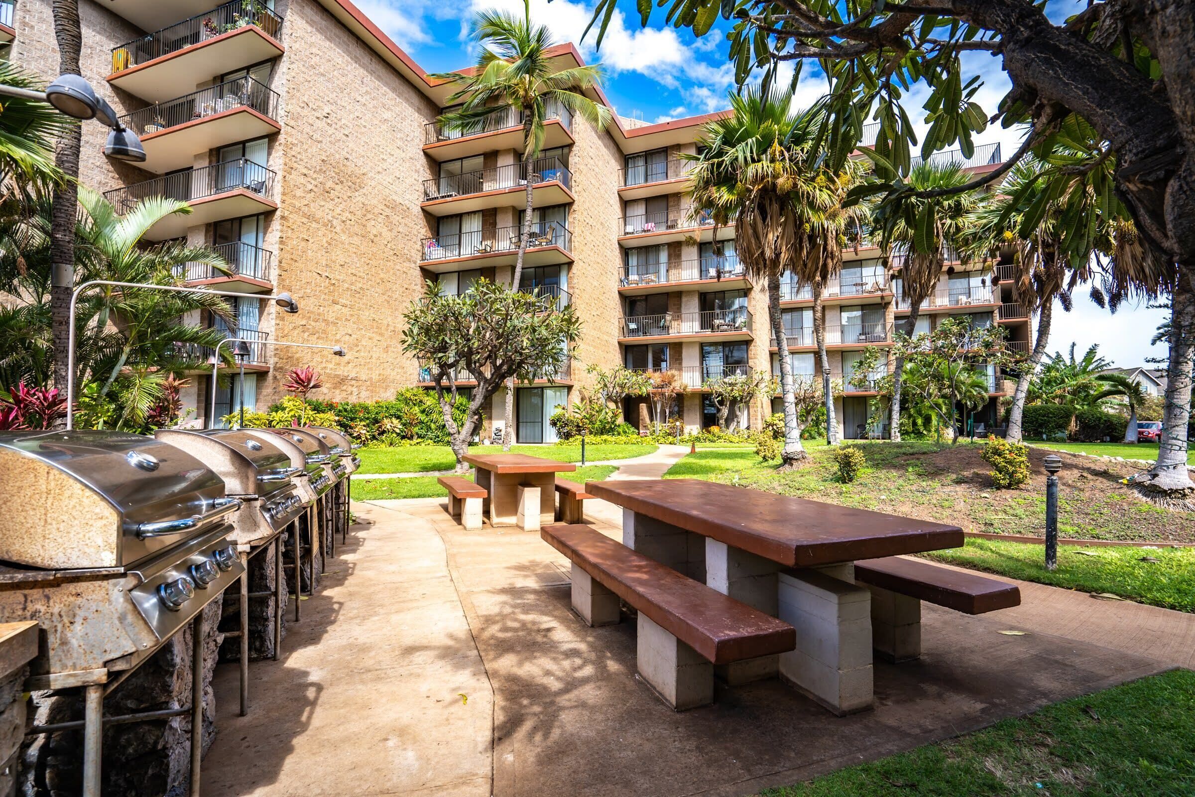 En innergård med utegrillar, picknickbord och en byggnad med balkonger.