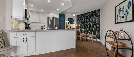 A modern kitchen with white cabinetry, a central island, and a dining area with a patterned wall.