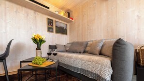 A cozy living area with a sofa, a table with a bottle of wine, glasses, and a vase of flowers.