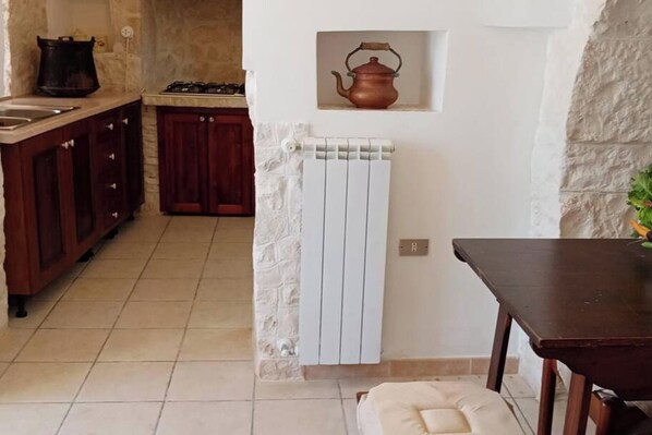 A kitchen with a stove, cabinets, and a radiator.