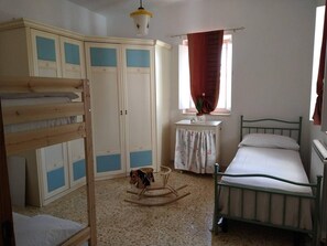 Un dormitorio con literas, una mesita pequeña, un caballo balancín y una ventana con cortinas.