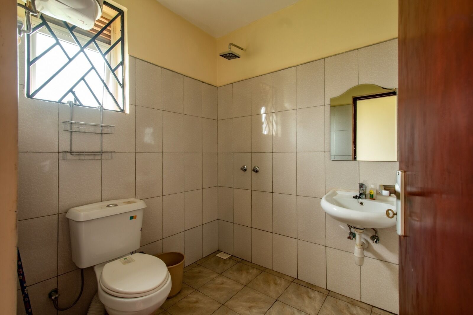 A small bathroom with a toilet, sink, and shower.