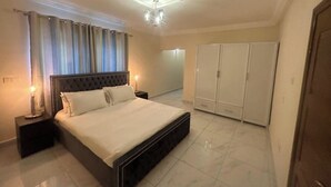 Un dormitorio con una cama grande, un armario y una mesita de noche con una lámpara.