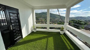 A balcony with artificial grass, two potted plants, and a black door. - 3 Bed Apartment Sleeps 6 - EnSuites, Parking, Wifi (Freetown)