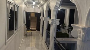 A corridor with white columns, a bench, and a potted plant. - 3 Bed Apartment Sleeps 6 - EnSuites, Parking, Wifi (Freetown)