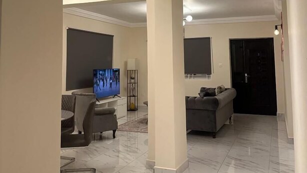 A spacious living area with a large TV, comfortable seating, and a tiled floor. - 3 Bed Apartment Sleeps 6 - EnSuites, Parking, Wifi (Freetown)