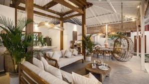 A spacious living area with wooden furniture, a hanging chair, and potted plants. - Villa Cyma by Alfred in Bali (Seminyak)