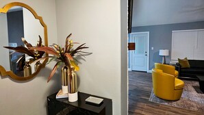 A modern living room with a wooden floor, a black console table, a mirror with a gold frame, and a yellow armchair. - Mama’s Modern House is family and pet friendly, large yard, quartz countertops  (Cypress)