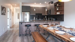 Cozinha moderna com ilha central, banquetas de bar e mesa de jantar para seis pessoas.
