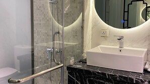A modern bathroom with a glass-enclosed shower, a white sink, and a marble countertop. - Mia Hotel (Feliz Hotel Binh Duong) (Ho Chi Minh City)
