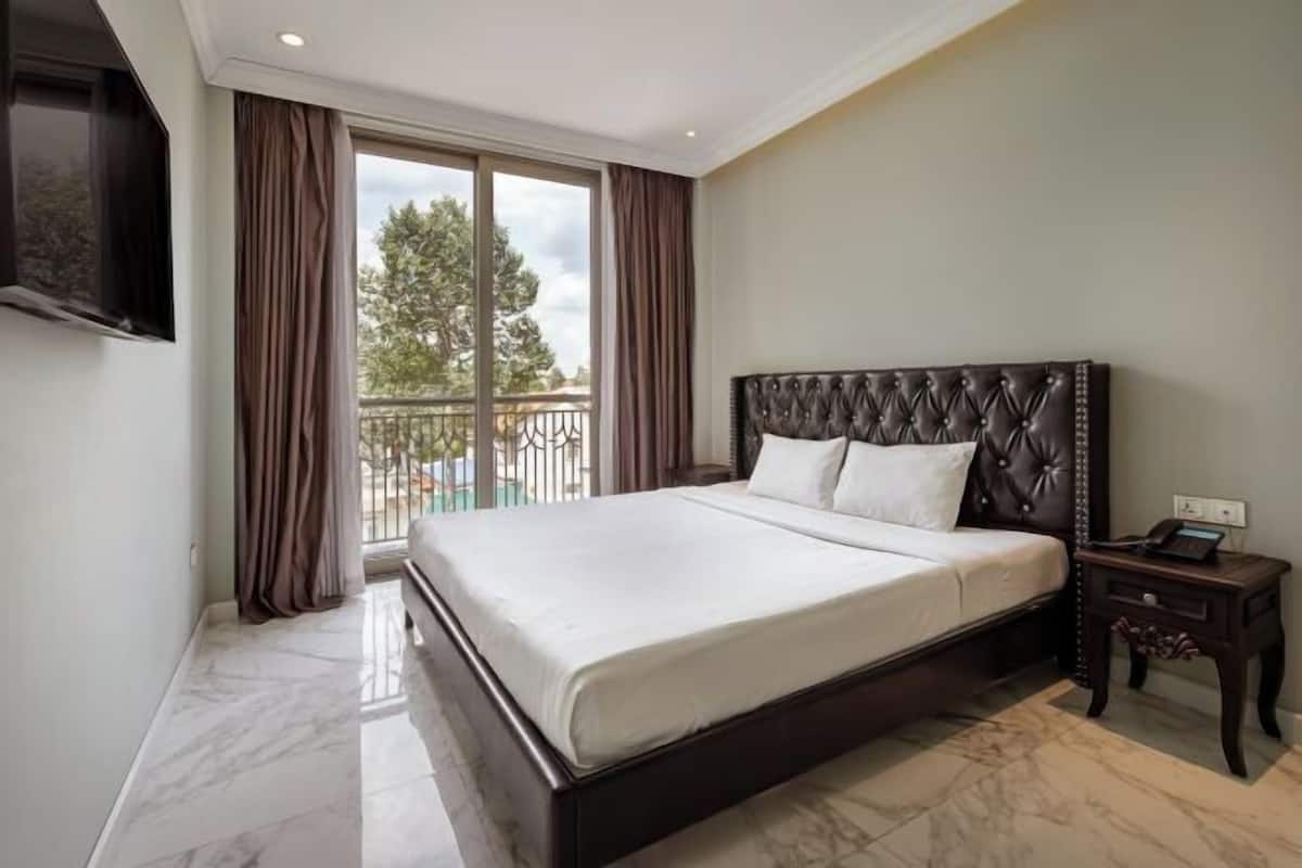 A bedroom with a large bed, a TV mounted on the wall, and a balcony view.