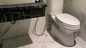 A bathroom with a white toilet, a sink with a marble countertop, and a mirror above the sink. - Mia Hotel (Feliz Hotel Binh Duong) (Ho Chi Minh City)