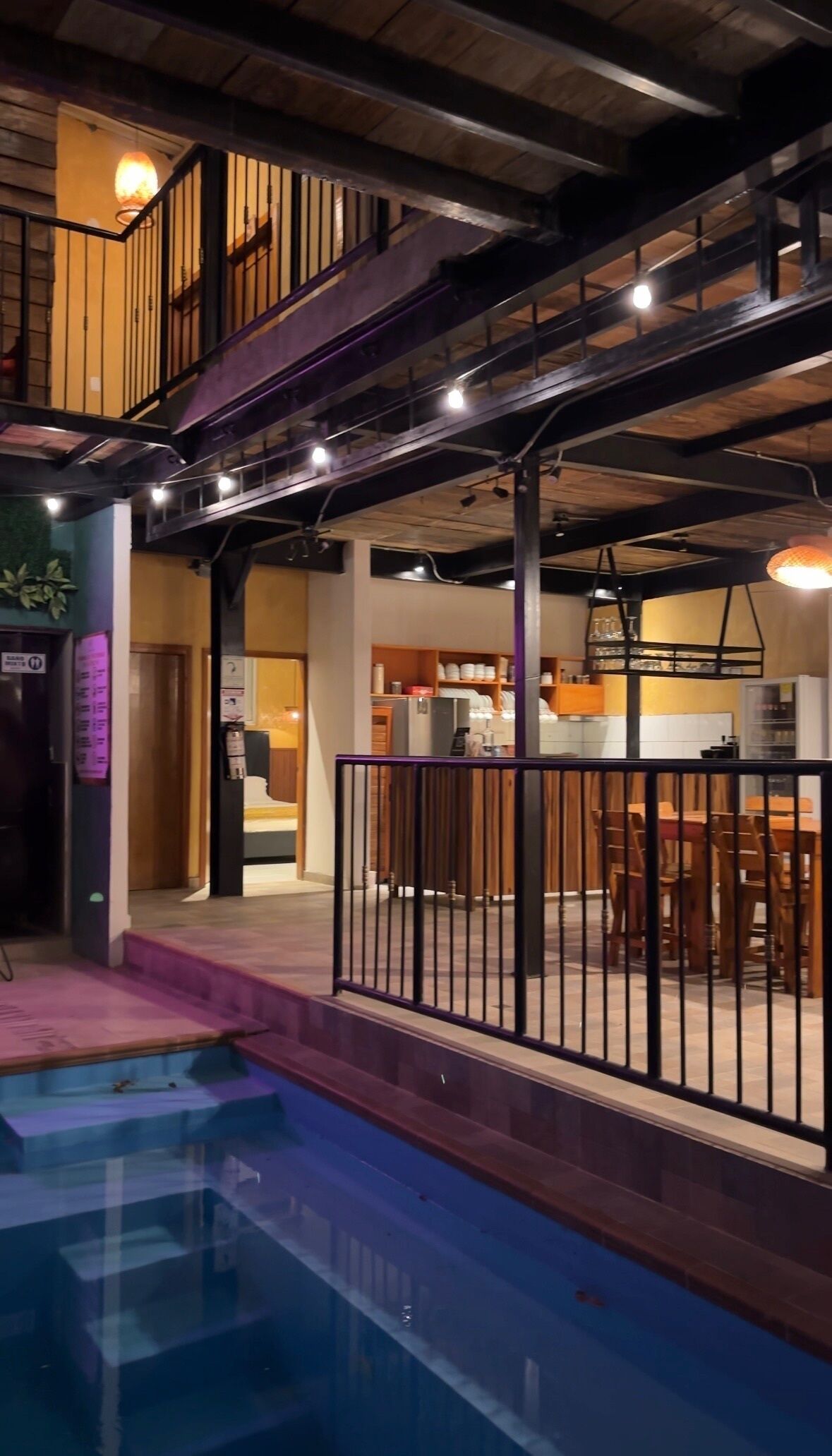 A multi-level hotel with a pool area, a staircase, and a dining area.