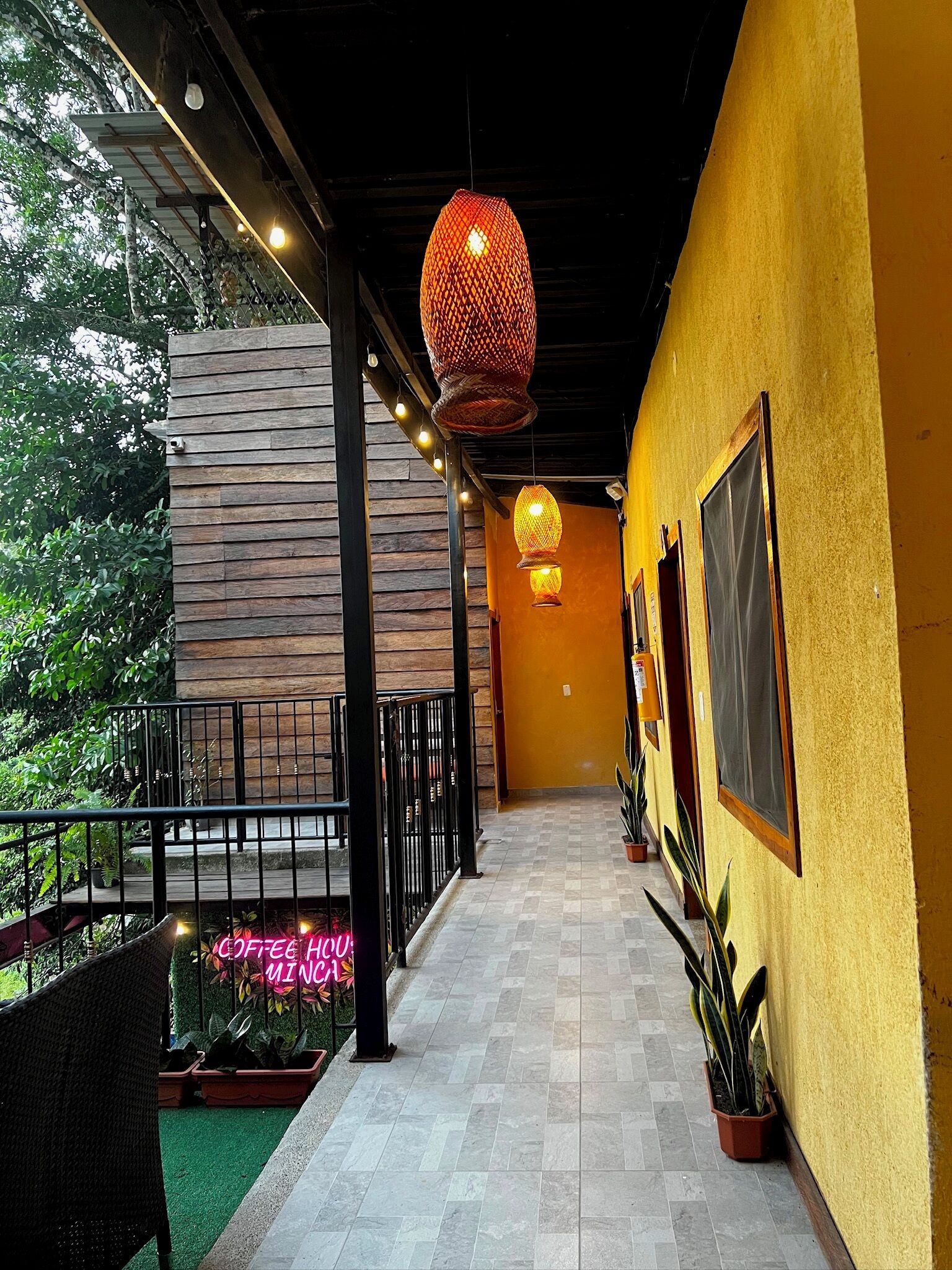 Un pasillo con pared de madera, luces colgantes y plantas en macetas.