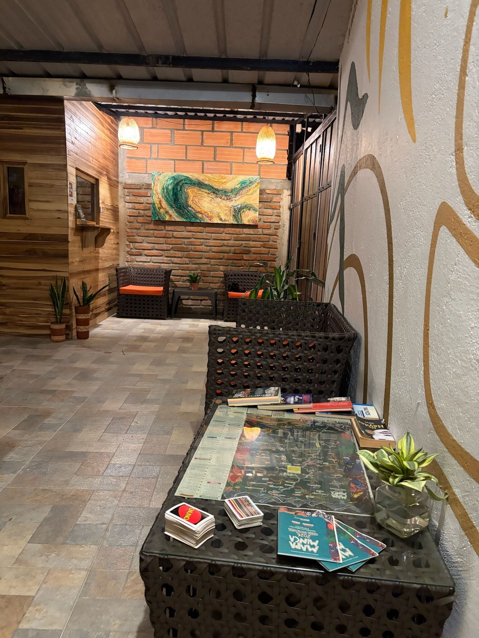 Un espace intérieur accueillant, avec un mur en briques, un luminaire suspendu et une table sur laquelle sont disposés divers objets.