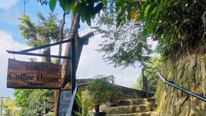 Un letrero de madera dice 'Coffee House Minca' en la parte superior de una escalera de piedra.