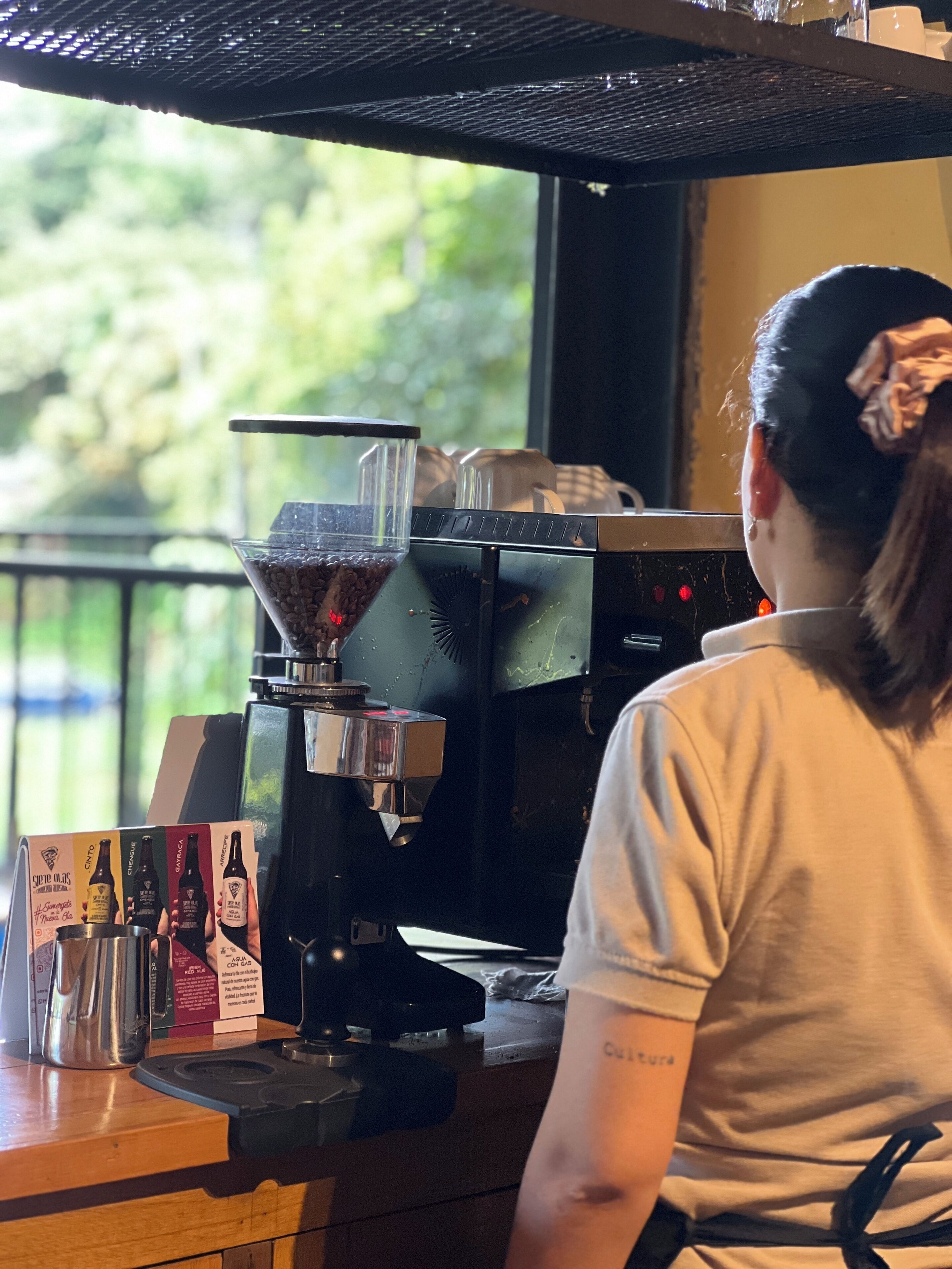 A coffee machine with a drip tray filled with coffee beans, a coffee press, and a display of coffee packaging.