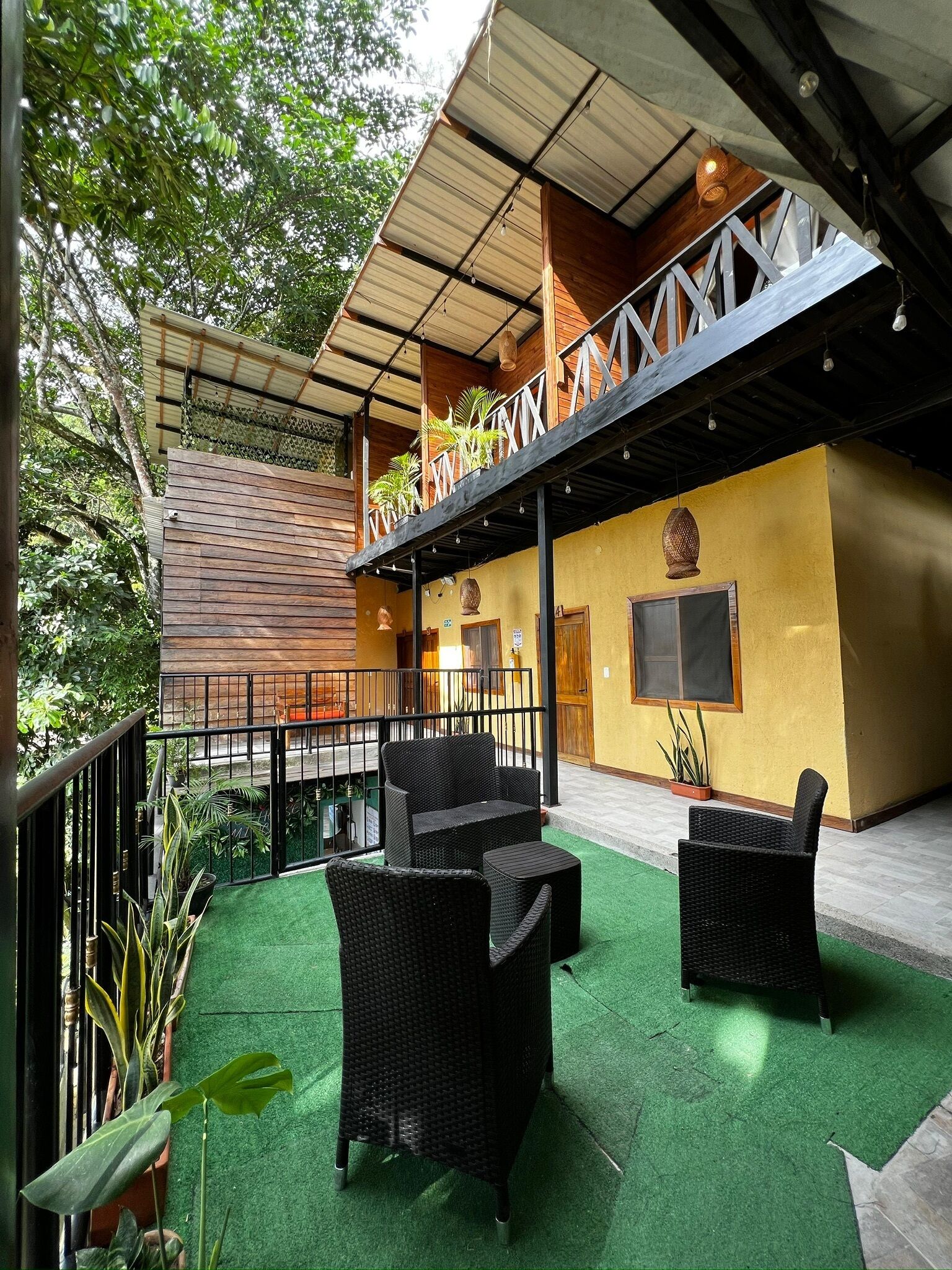 Un espacio de estar al aire libre con mobiliario de mimbre y piso de césped artificial verde.