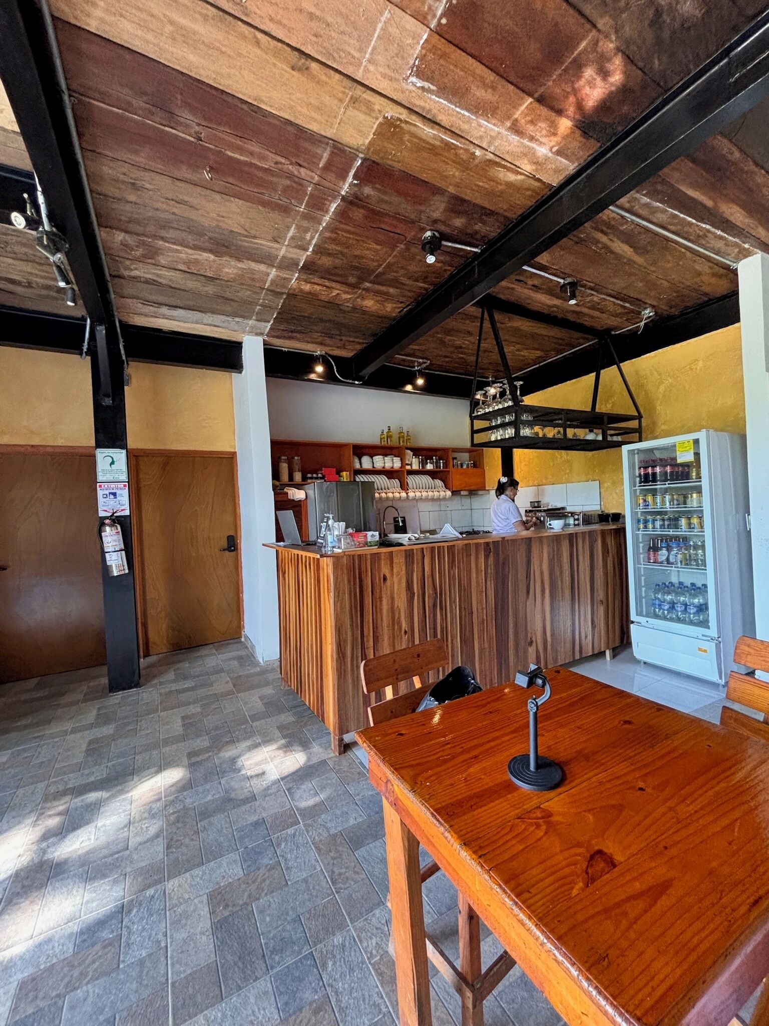 A restaurant interior with a wooden counter, a seating area, and a beverage dispenser.