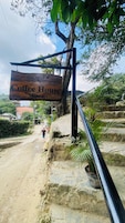 Un letrero de madera que dice 'Coffee House Minca' colgado de un poste de metal.