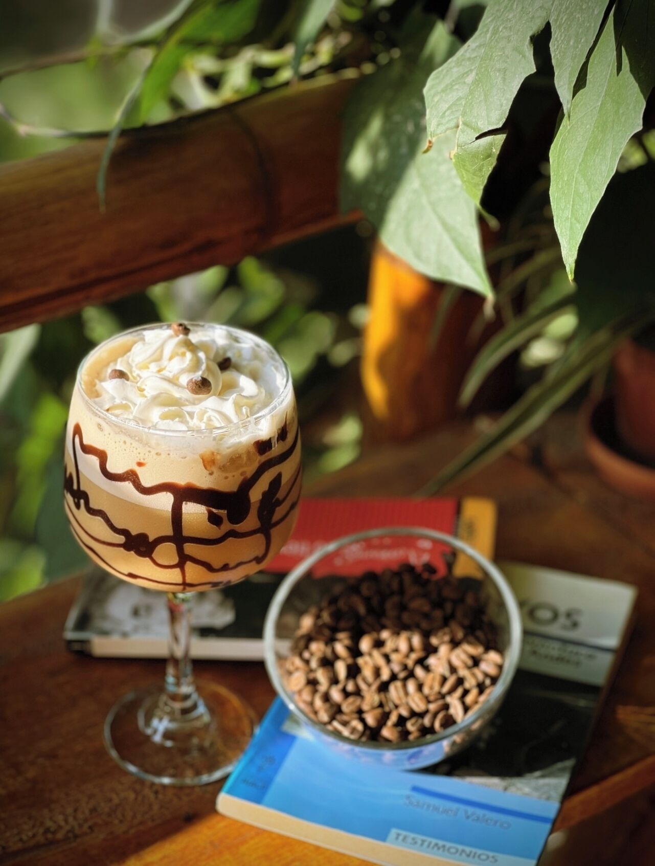 Ein Dessert im Glas auf einem Tisch mit einem Buch und Kaffeebohnen in der Nähe.