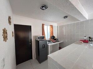 A compact kitchen with a microwave, refrigerator, and a small countertop. - Secretos del Sol (Acapulco)