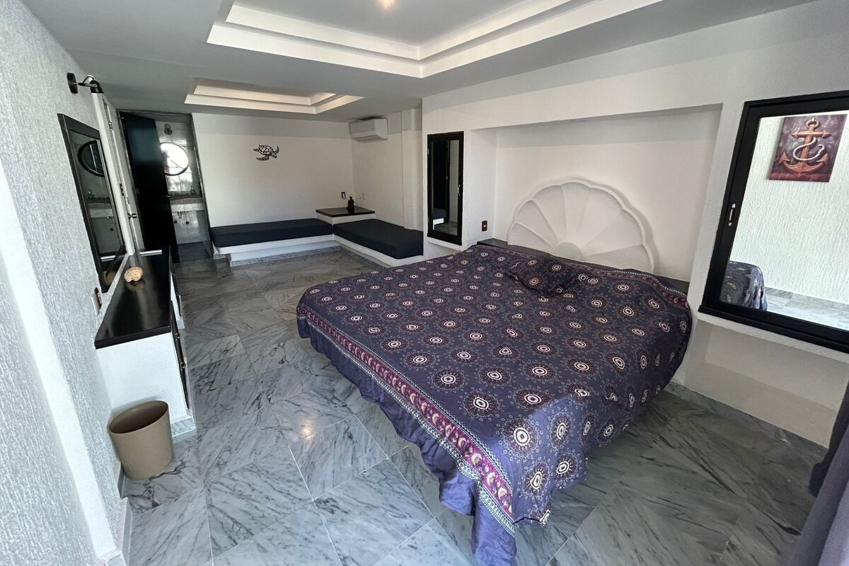 Un dormitorio con una cama grande, un banco empotrado, un tocador y un espejo.