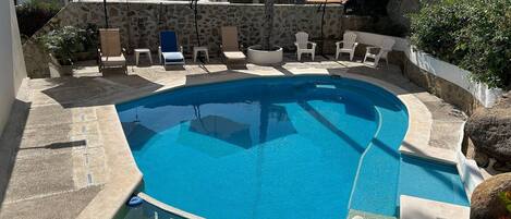 Una piscina al aire libre, sillones reclinables de piscina