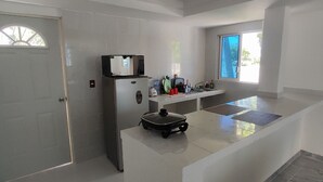 Una cocina moderna con refrigerador, microondas y una pequeña isla con pileta.