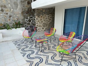 A patio with four colorful wire chairs and a patterned tile floor. - Secretos del Sol (Acapulco)