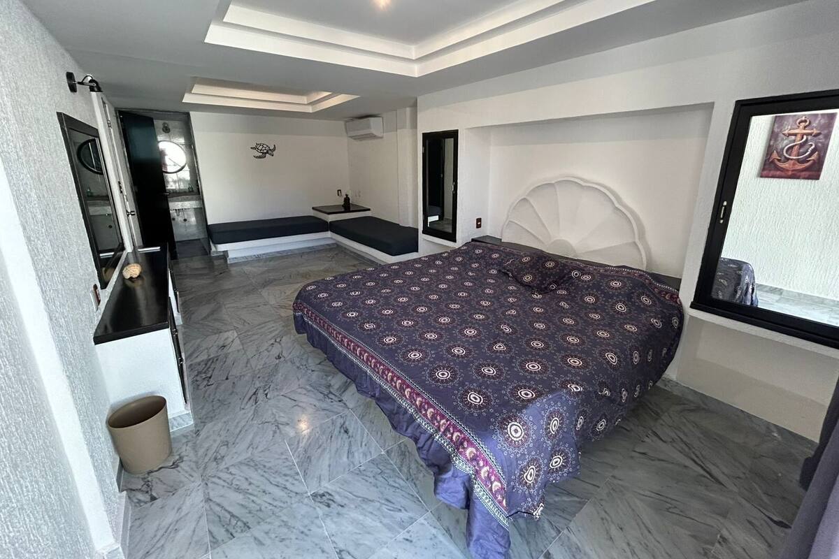 Une chambre à coucher avec un grand lit, une banquette intégrée, une coiffeuse et un miroir.