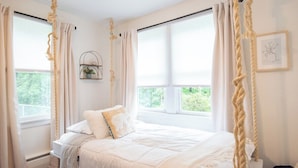 A bedroom with a bed, curtains, a window, and a wall-mounted shelf.